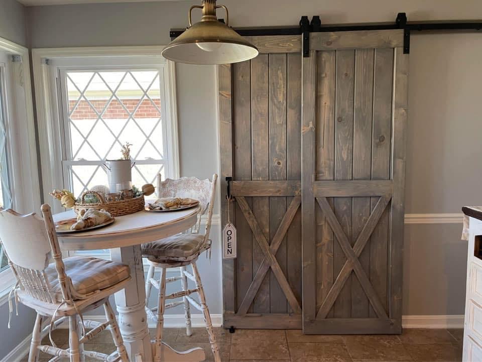 Pair of gray stained double barn doors on a black rail in a breakfast nook