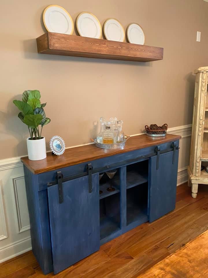 Navy blue sliding barn door buffet with stained wood top and matching floating shelf