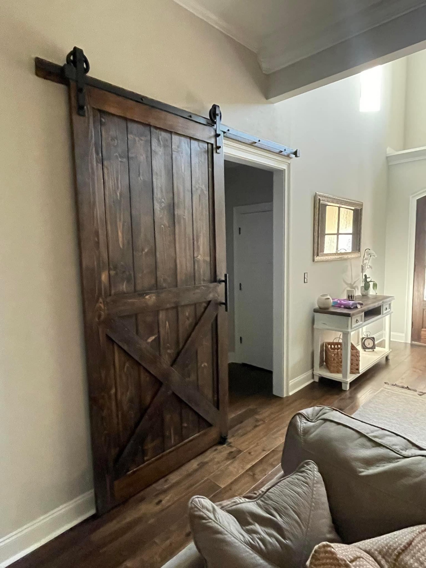 Dark stained sliding barn door on black hardware in a hallway